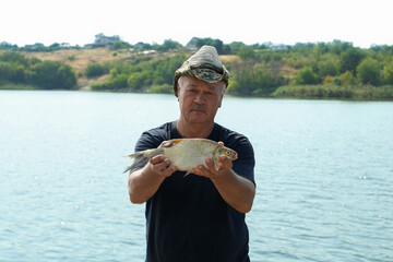 Sticker - Fisherman holding caught fish near lake outdoors