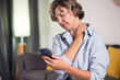© Aleksej - Woman holding mobile phone suffering neck pain caused by bad posture. People and health concept