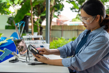 Asian woman programming microcontroller to control analog dissolved oxygen sensor. Using electric meter to monitor microcontroller operation. Agriculture and aquaculture. Internet of Things (IoT)