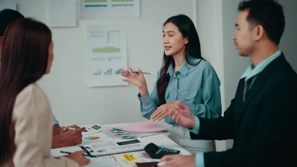 Fototapete - Asian businesswoman stands and speaks during a financial meeting with her team. They are discussing data and developing strategies for success
