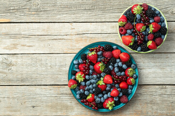 Wall Mural - Mix of ripe colorful berries in bowl photography . Blueberry , strawberry , raspberry , blackberry and red currant . Top view