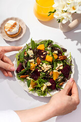 Wall Mural - Woman with salad and orange juice sitting at white table