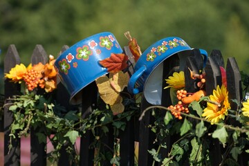 Canvas Print - Tow blue metal pots decorated with flowers on wooden fence in countryside