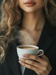 © Lightgeo - A woman in a stylish outfit holds a steaming cup of coffee, enjoying a moment of warmth and comfort in a cozy ambiance.