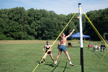 Outdoor volleyball player poking the ball over the net