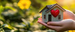 © Rutchaneewan - Hands hold a miniature house with a heart outdoors, reflecting the essence of home sweet home and real estate dreams on a sunny summer day.