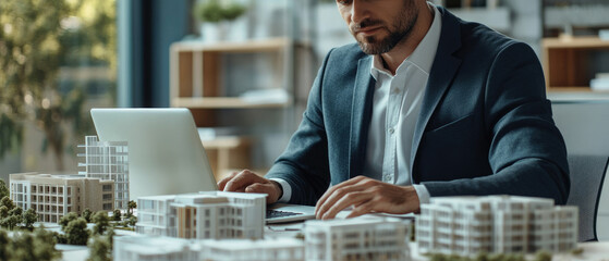 A businessman focuses on property management in an office setting, surrounded by housing development models, illustrating the dynamic world of real estate planning and strategy.