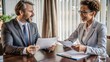 © Bounpaseuth - Two businesspeople exchanging documents in a formal negotiation setting, contract signing, finalizing an agreement