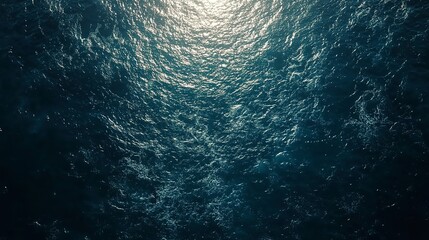 Wall Mural - A bird's eye view of a dark blue ocean, the water rippling and glistening in the sunlight 