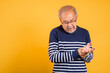 © sorapop - Portrait Asian old man with glasses holding his painful hand studio shot isolated yellow background, senior man pensioner feeling pain hand pain wrist bone joint problem
