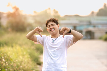 a man standing with a thumbs down. The man acted like someone was underestimating something. set in nature on a sunny afternoon.