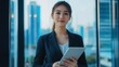 © Bijac - empowered asian businesswoman confident young professional in sleek office attire stands tall holding a tablet modern workspace with glass walls and city skyline visible in background