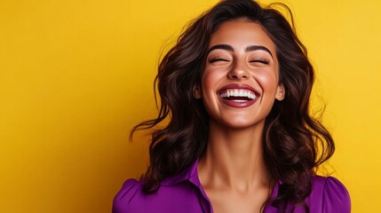 Wall Mural - A beautiful woman with long brown hair is laughing while wearing a purple shirt and standing in front of a yellow background.