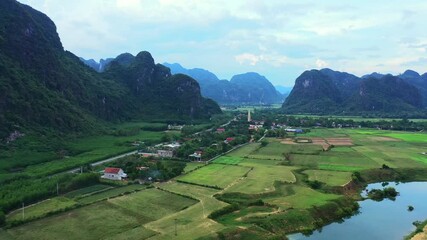 Wall Mural - Nature, mountains and aerial of village by river for travel destination, tourism and community with houses. Countryside, rural and drone view of landscape, buildings and neighborhood in Vietnam