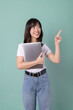 © Jirawatfoto - A young woman holding laptop smiles and points upwards, suggesting an idea or inspiration. Her expression is cheerful and engaging, creating positive atmosphere