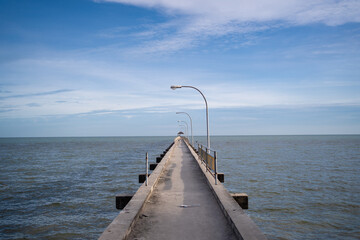 Perspective view of a jetty on the sea with sunlight illuminated on the bridge.