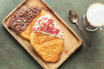 Flat Croissants, Trendy Pastry, Croissant with chocolate icing and pastry sprinkles. Top view