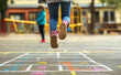 © Curioso.Photography - Children's feet mid-air as they jump on a playground covered in colorful chalk drawings.