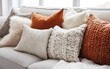 © AZ Studio - Decorative throw pillows with rich textures and warm tones arranged on a cozy sofa in a well-lit living room during autumn