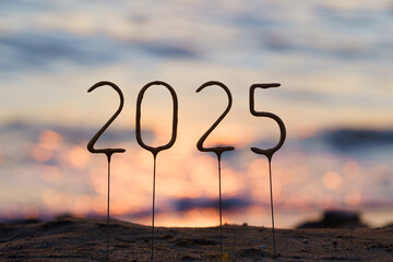 Numbers 2025 on a stick representing the year against the background of sparkling blue water and sunset on the beach. New Year and Christmas greetings, celebration, greeting colleagues and loved ones