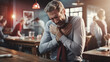 © Bonsales - Middle-aged man experiencing chest pain while sitting in a restaurant, showing signs of discomfort and distress