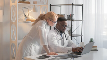 Medical teamwork. Healthcare expertise. Modern clinic. Man physician typing diagnosis treatment at laptop with woman doctor at hospital workplace.