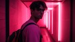 © Anna - A young man stands in a vibrant neon corridor, illuminated by pink lights, turning to gaze towards the camera as he walks through the urban space at night