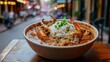 © fivan - A bowl of rich crab gumbo with rice, served on a wooden table with a festive New Orleans street parade in the background
