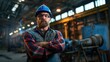 © Anna - A confident worker stands with arms crossed in an industrial workshop, wearing a plaid shirt, hard hat, and safety glasses. The background features machinery and bright lights