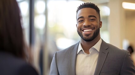 Wall Mural - A suited male employee standing and smiling while interacting with a customer in a professional setting, conveying trust and satisfaction.