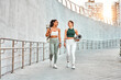 © HBS - Two attractive modern sports women are walking holding mats for fitness training, yoga and joyfully chatting. Sincere friendship and sports lifestyle.Copy space.