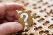 © Vera - close-up photo of a person's hand holding a puzzle piece with a question mark symbol on it. The image captures the concept of business problem solving and critical thinking.