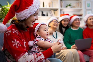 Asian family on Christmas Day. Everyone is happy together in a Christmas themed room filled with presents and orange lights.