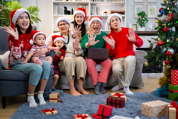 Asian family on Christmas Day. Everyone is happy together in a Christmas themed room filled with presents and orange lights.