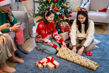 Asian family on Christmas Day. Everyone is happy together in a Christmas themed room filled with presents and orange lights.