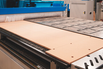 Poster - A woodworking machine is in use, with a large piece of wood being cut into smaller pieces. The machine is surrounded by blue and white, giving it a clean and professional appearance