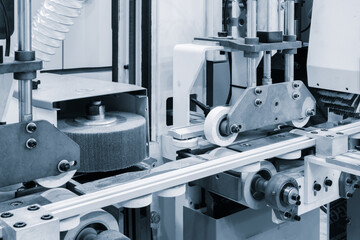 Poster - A machine is in the process of cutting a piece of wood. The machine has a large grinding wheel and a white wheel