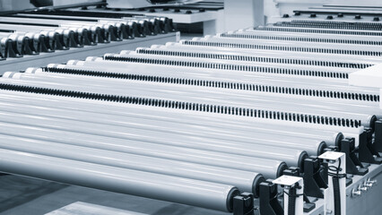Leinwandbilder - A row of metal tubes are lined up in a factory. The tubes are white and black, and they are all the same length. Concept of order and precision, as the tubes are arranged neatly and uniformly