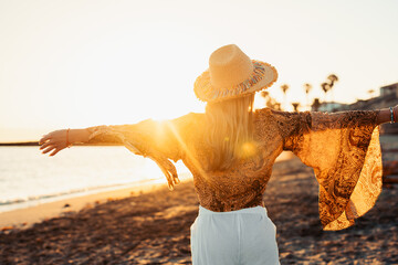 One happy beautiful woman walking on the sand of the beach enjoying and having fun at the sunset of the day. Leisure time on vacations, freedom concept.