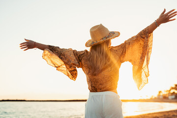 Wall Mural - One happy beautiful woman walking on the sand of the beach enjoying and having fun at the sunset of the day. Leisure time on vacations, freedom concept.