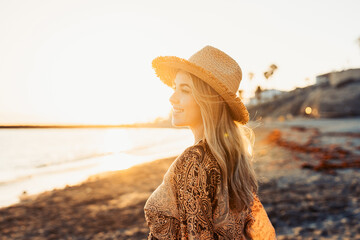 Wall Mural - One happy beautiful woman walking on the sand of the beach enjoying and having fun at the sunset of the day. Looking at the sea smiling..