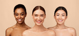 Three Happy Diverse Girls Wrapped In White Towels Posing Standing On Gray Studio Background, Smiling To Camera. Body Care Concept