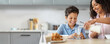 © Prostock-studio - African American mother pours milk into a glass for her smiling son at a breakfast table. They are in a bright and modern kitchen surrounded by delicious food.