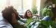 © gunzexx png and bg - A couple relaxes on a sofa surrounded by lush indoor plants, symbolizing tranquility and comfort in a cozy, nature-inspired living space.