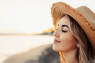 Wall Mural - Portrait of one young woman at the beach closing eyes enjoying free time and freedom outdoors. Having fun relaxing and living happy moments..