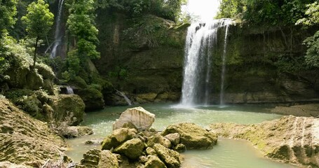 Canvas Print - Aerial drone of waterfall in a tropical forest surrounded by green vegetation. Ben-Ben Falls in mountain jungle. Negros, Philippines.