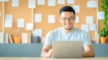 Smiling young man working online on laptop in modern workspace..