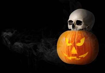 Wall Mural - Spooky glowing jack o'lantern and scary skull in smoke on black background. space for text. Halloween celebration