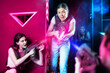 © JackF - Young women in laser tag studio play safe military tactical game, hide behind barrier, protect their team from enemy, use radiation simulators