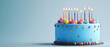 © wannee - A vibrant blue birthday cake decorated with colorful icing, sprinkles, and lit candles, perfect for celebration and joy.